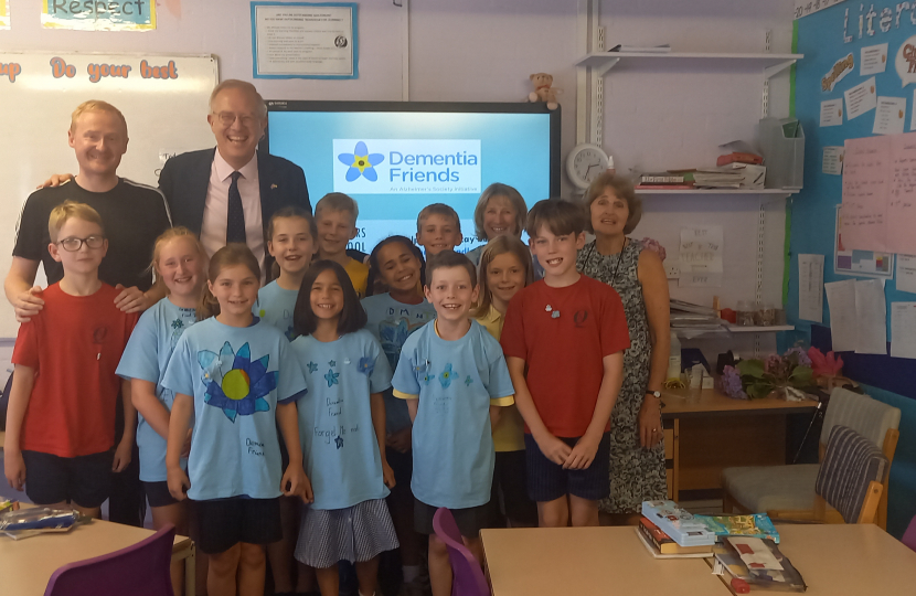 Photo shows John with Headteacher, Michael Wade, and pupils and staff at the school.